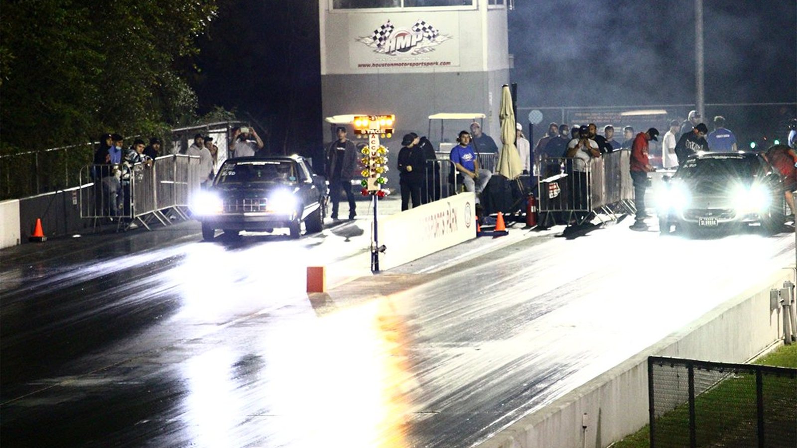 Cars lit up at night under floodlights at a Houston street car takeover